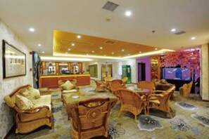 A hotel lobby with wicker furniture, a reception desk, and a television. - Aulicare Hotel (Dalian)