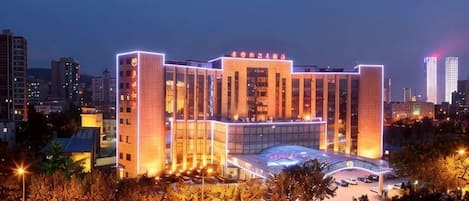 Hotel de vários andares com design moderno, apresentando um átrio central e área de estacionamento.