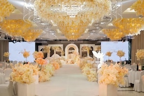 A venue with a stage, floral arrangements, and a seating area. - Aulicare Hotel (Dalian)