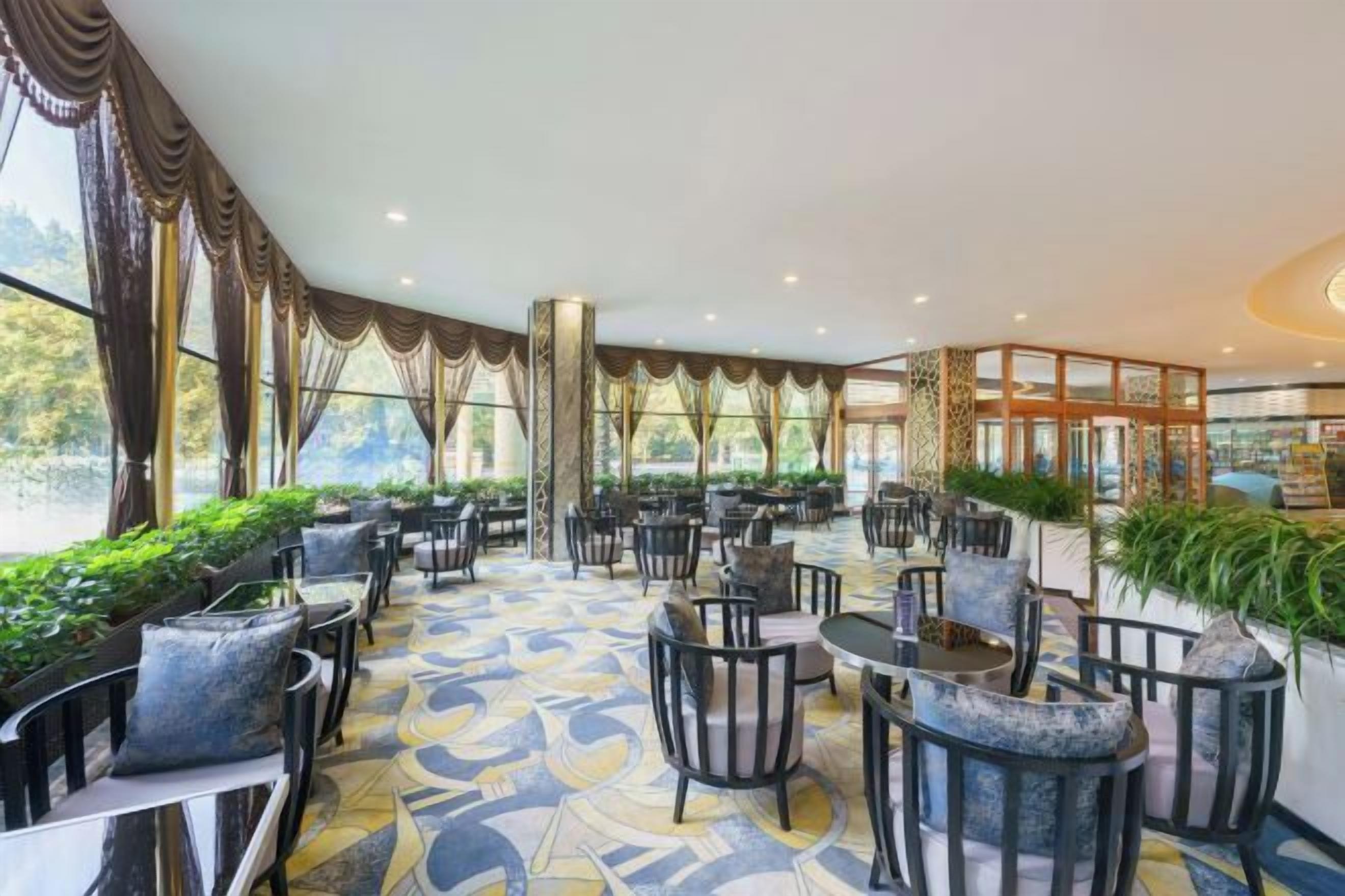 A spacious indoor area with multiple seating arrangements, including tables and chairs, and a patterned floor.
