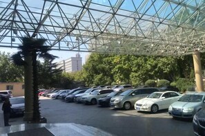 Un estacionamiento techado con varios autos y una palmera.
