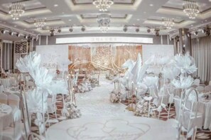 A formal event space with a stage, floral decorations, and a white carpet. - Aulicare Hotel (Dalian)