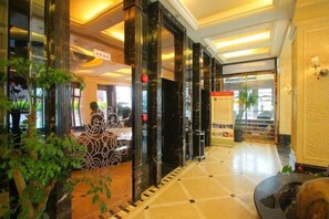 A hotel lobby with a reception desk, a plant, and a signboard. - Andersen Culture (Shanghai)