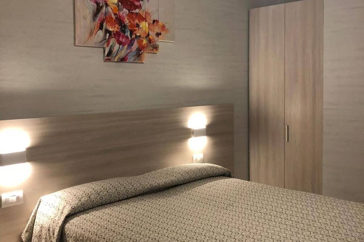 Een slaapkamer met een bed, bedlampen, een plafondventilator en een kledingkast.