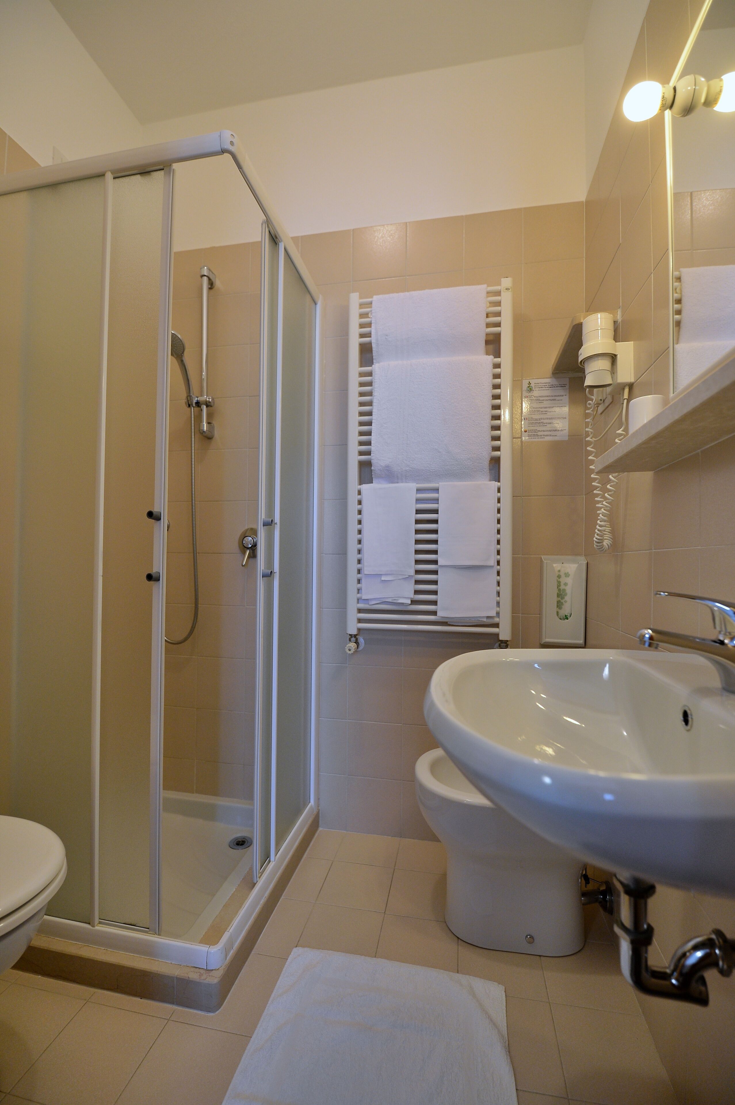 Un baño con ducha de mampara de vidrio, inodoro y lavamanos.