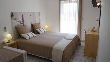 Un dormitorio ordenado con una cama grande, lámparas de noche, una mesita de madera y una ventana con cortinas.