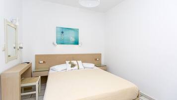 Un dormitorio ordenado con cama, mesitas de noche, escritorio y silla.