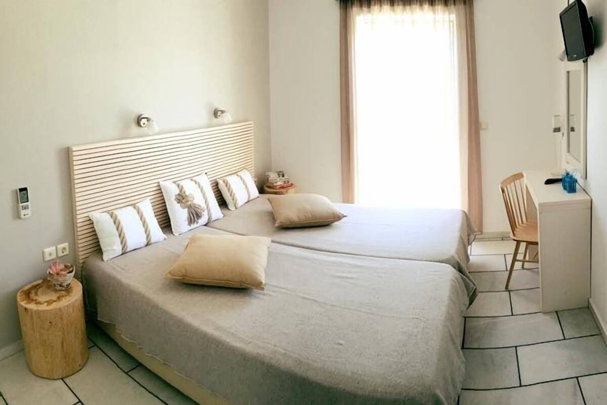 A bedroom with two beds, a desk, and a chair.