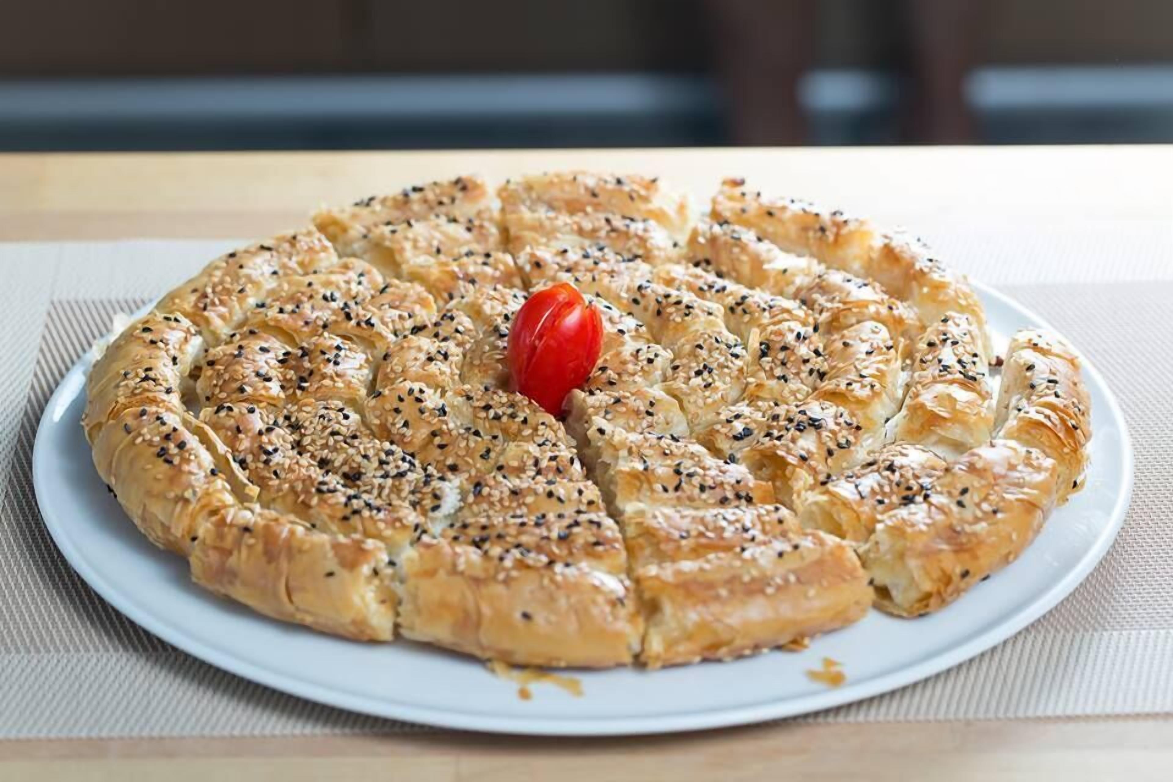 Un pastelito redondo con semillas de sésamo sobre un plato blanco.