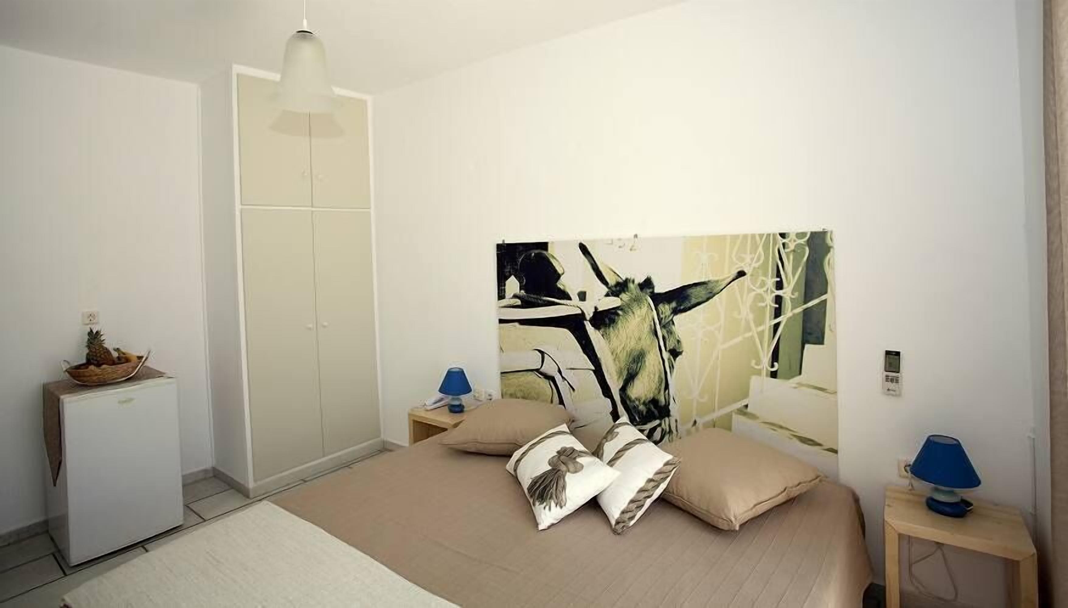 A bedroom with a bed, a wardrobe, a desk, and a lamp.
