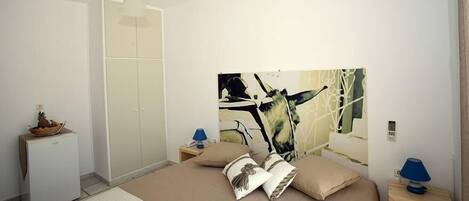 A bedroom with a bed, a wardrobe, a desk, and a lamp.