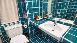 Une salle de bain avec des toilettes, un lavabo et des murs recouverts de carreaux bleus.