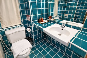 A bathroom with a toilet, sink, and blue tiled walls. - Villa Cha Cha Banglumphu (Bangkok)