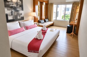 Habitación de hotel con una cama grande, un escritorio, una silla, una lámpara y vistas al exterior.