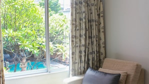 Une petite pièce agréable et chaleureuse, avec un lit simple, une fenêtre avec des rideaux et une vue sur la verdure.