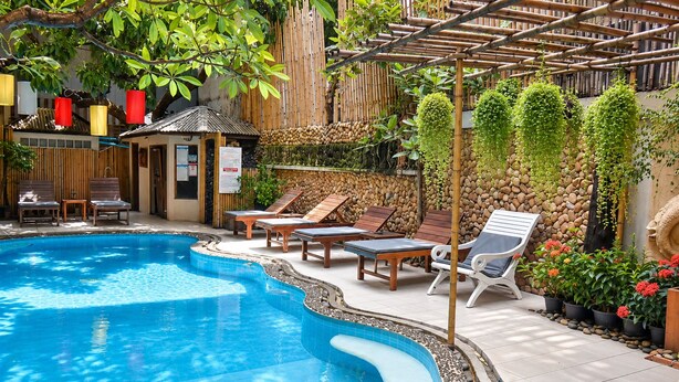 Une piscine avec des chaises longues et une pergola en bambou.