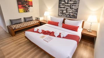 Una habitación de hotel con una cama grande, un sofá, dos mesitas de noche con lámparas y obras de arte en las paredes.