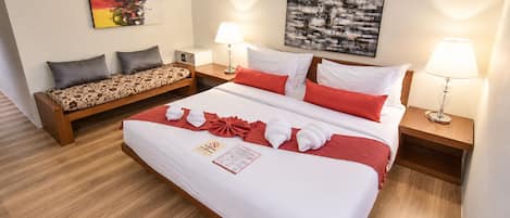 A hotel room with a large bed, a sofa, two bedside tables with lamps, and artwork on the walls.