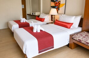 Habitación de hotel con dos camas, ropa de cama roja y blanca, un plaid rojo, una lámpara y un cuadro en la pared.