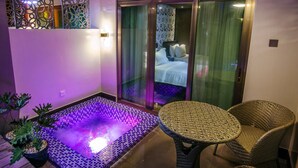 Un área de spa con suelo calefaccionado, una sala acristalada con una cama y muebles de mimbre.