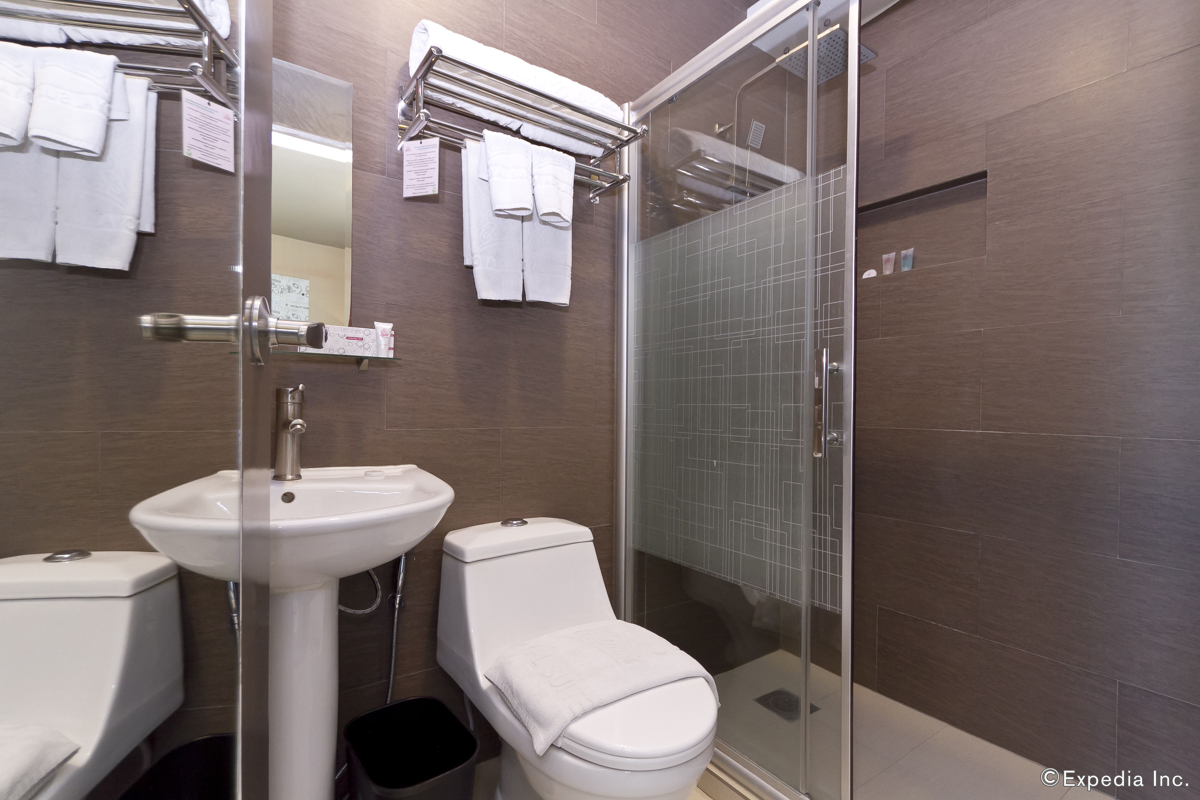 Et moderne badeværelse med en glasafskærmet brusekabine, en hvid vask og et toilet.