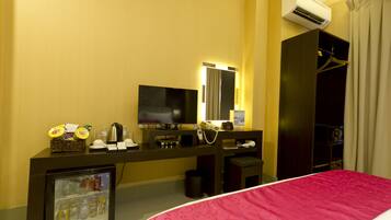 A hotel room with a bed, a TV, a minibar, a mirror, and a wardrobe.
