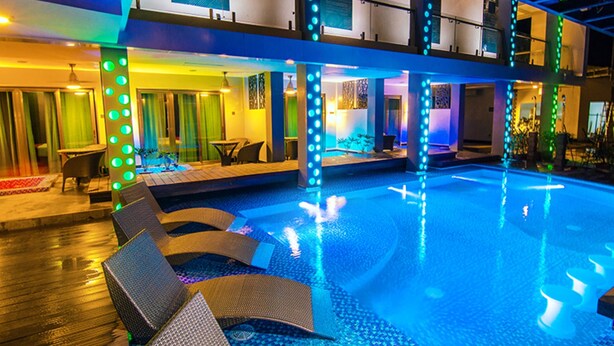 Una piscina interior de varios niveles con iluminación azul, sillones de descanso y una zona de bar.