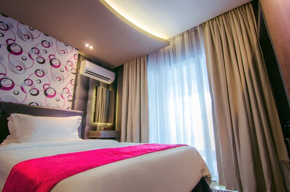 A hotel room with a large bed, an air conditioning unit, and a window with curtains. - Eloisa Royal Suites (Lapu-Lapu)