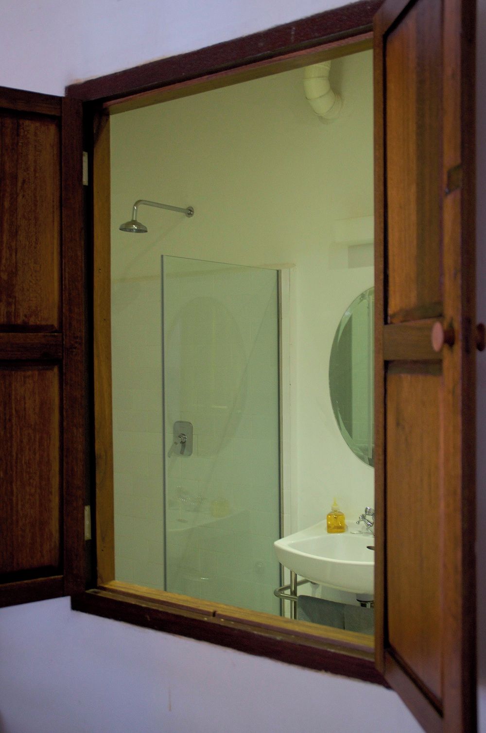 A bathroom with a glass shower enclosure, a sink, and a mirror.