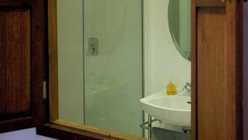 A bathroom with a glass shower enclosure, a sink, and a mirror.