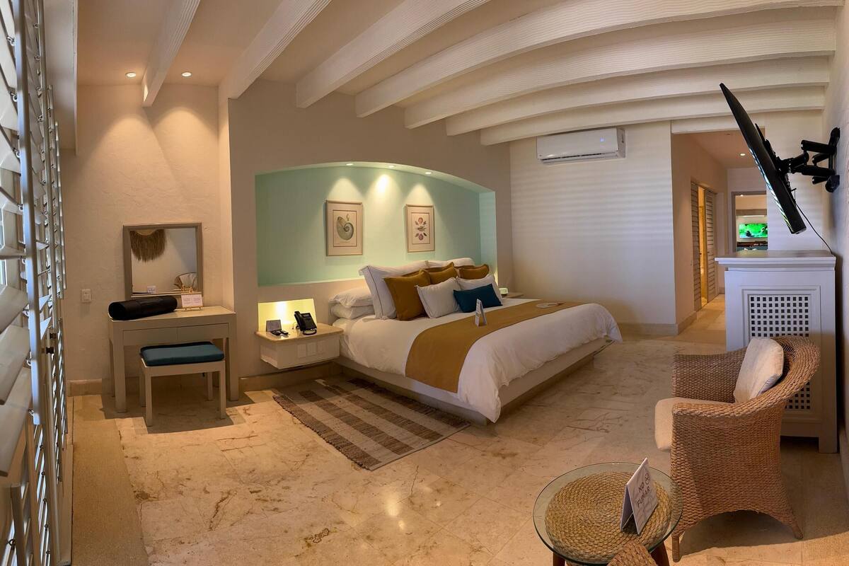 Een hotelkamer met een bed, nachtkastje, stoel en decoratieve wandversiering.