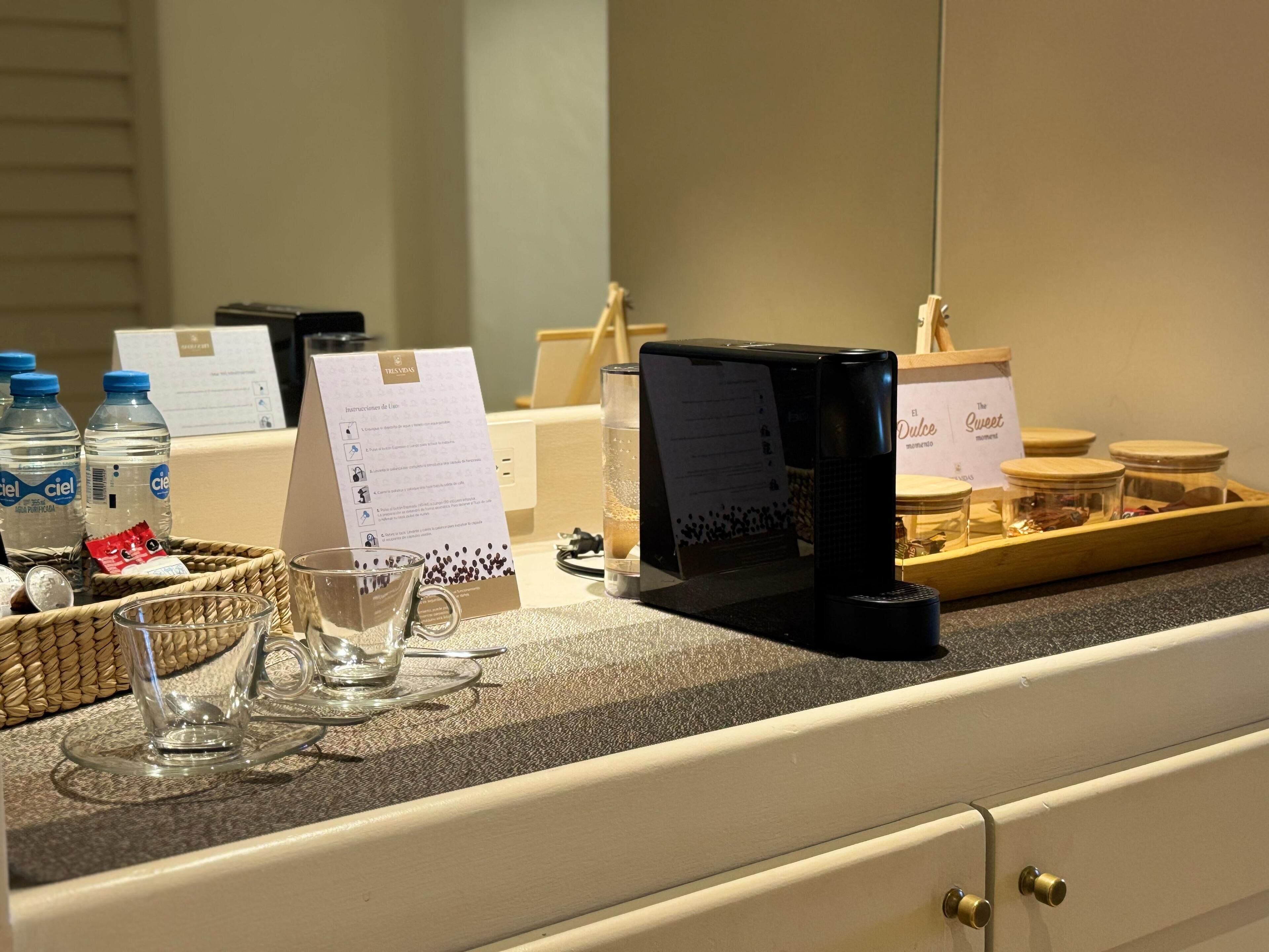 A hotel reception area with a counter displaying water bottles, a coffee machine, and a menu.