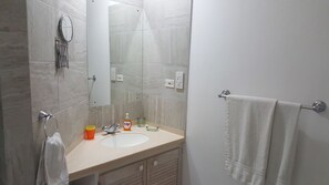 A bathroom with a sink, mirror, towel rack, and shower. - Shades (Paynes Bay)