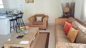 Ein Wohnzimmer mit einer Couch, einem Couchtisch und einem Essbereich mit einem Barhocker.
