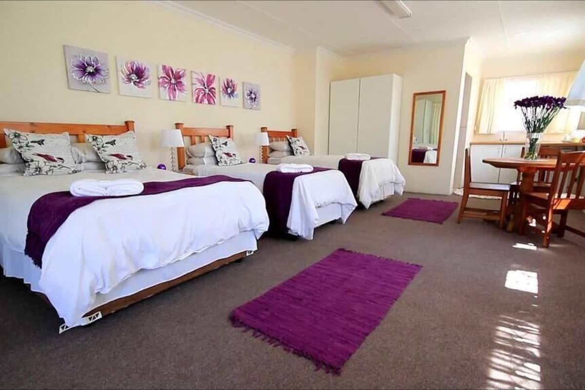 A hotel room with two beds, a dining area, and a bathroom.