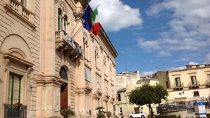 Un bâtiment historique à l’architecture classique, doté d’une cour pavée et orné de drapeaux européens.