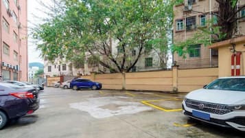 Un estacionamiento con autos, un árbol y edificios.