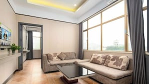 A modern living room with a sectional sofa, a glass coffee table, and a large window with curtains. - Meiyutu International Hotel (Shenzhen Bao'an Branch) (Shenzhen)