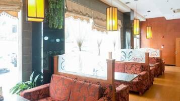 A hotel lobby with a seating area featuring patterned sofas and a decorative wall.