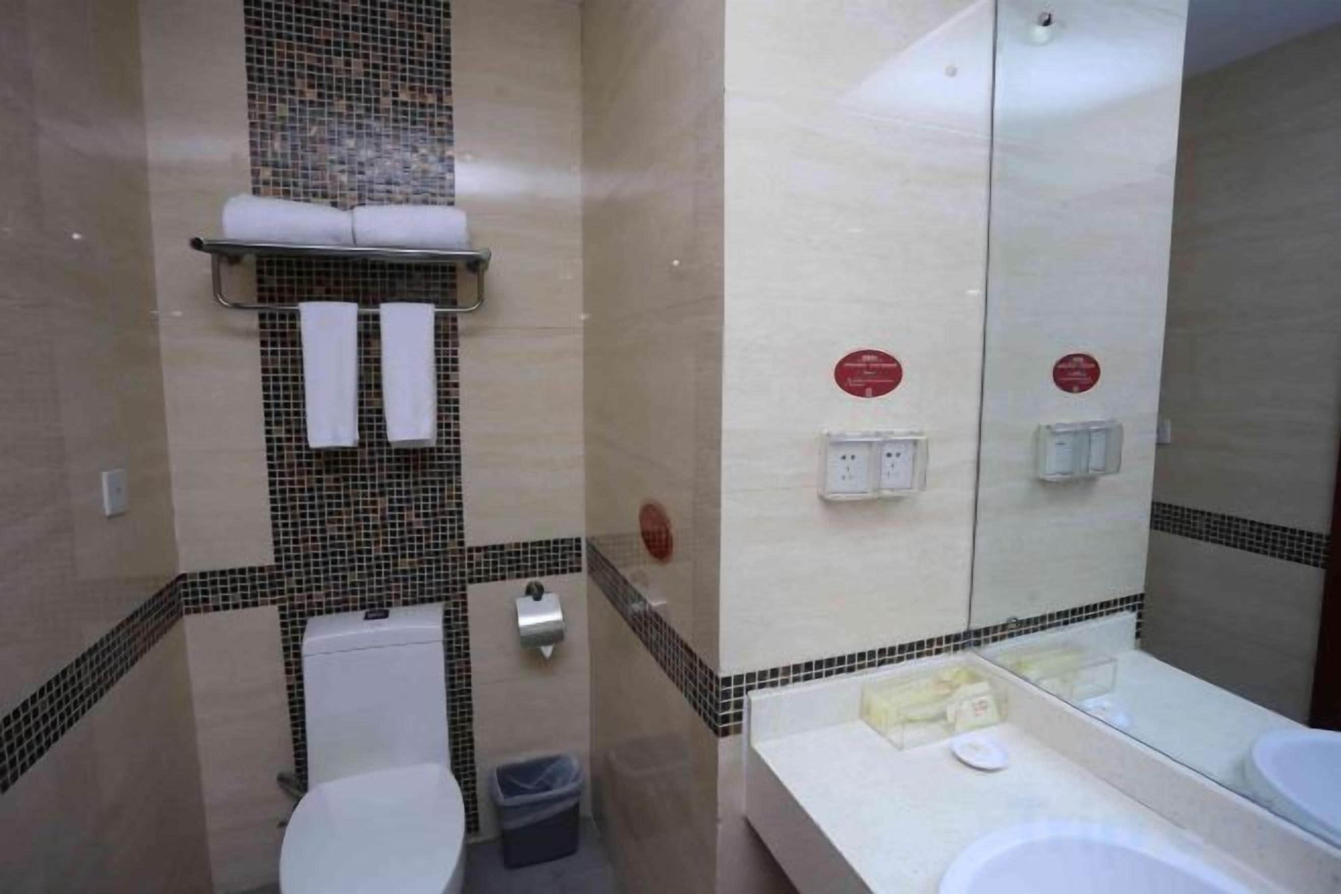 Un baño con inodoro, lavamanos y espejo.