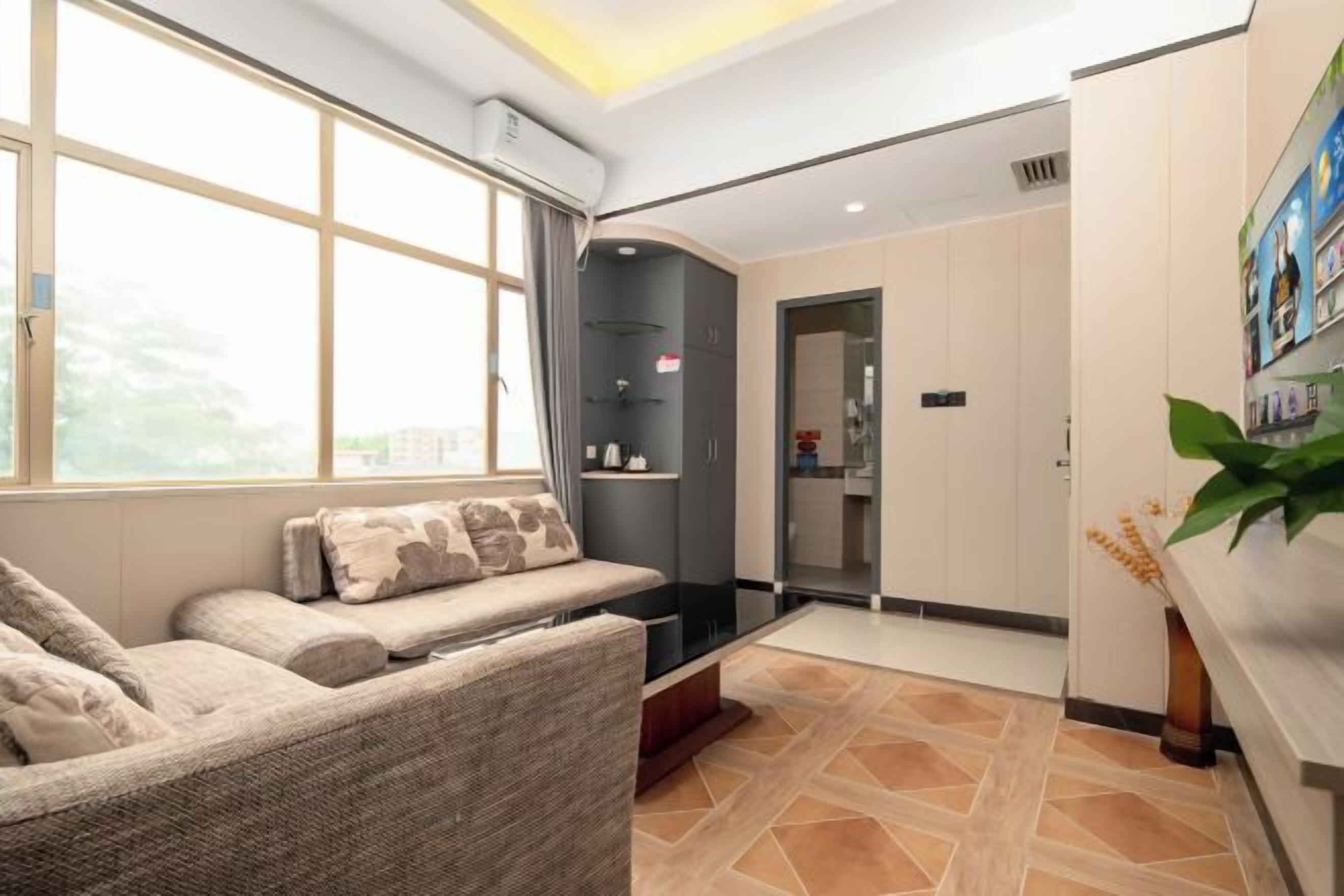 Ein modernes Hotelzimmer mit großem Fenster, einer Couch, einem kleinen Tisch und einer Rezeption.