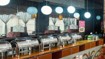 A buffet setup with multiple serving stations, a counter with food items, and hanging light fixtures.