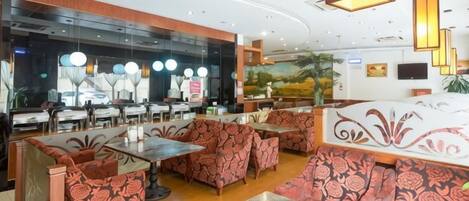 A restaurant with booths and tables, a counter, and a mural on the wall.
