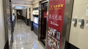 A hotel corridor with a red welcome sign, a reception desk, and a sign indicating the hotel name. - Prince Hotel (Kowloon)