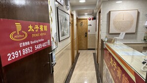 A hotel reception area with a red signboard displaying the hotel's name and contact information. - Prince Hotel (Kowloon)