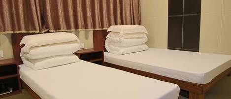 Two single beds with white linens, wooden headboards, and a wall-mounted light fixture.