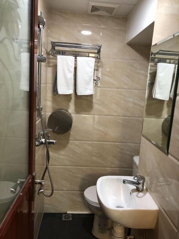 A bathroom with a glass-enclosed shower, a toilet, and a sink.