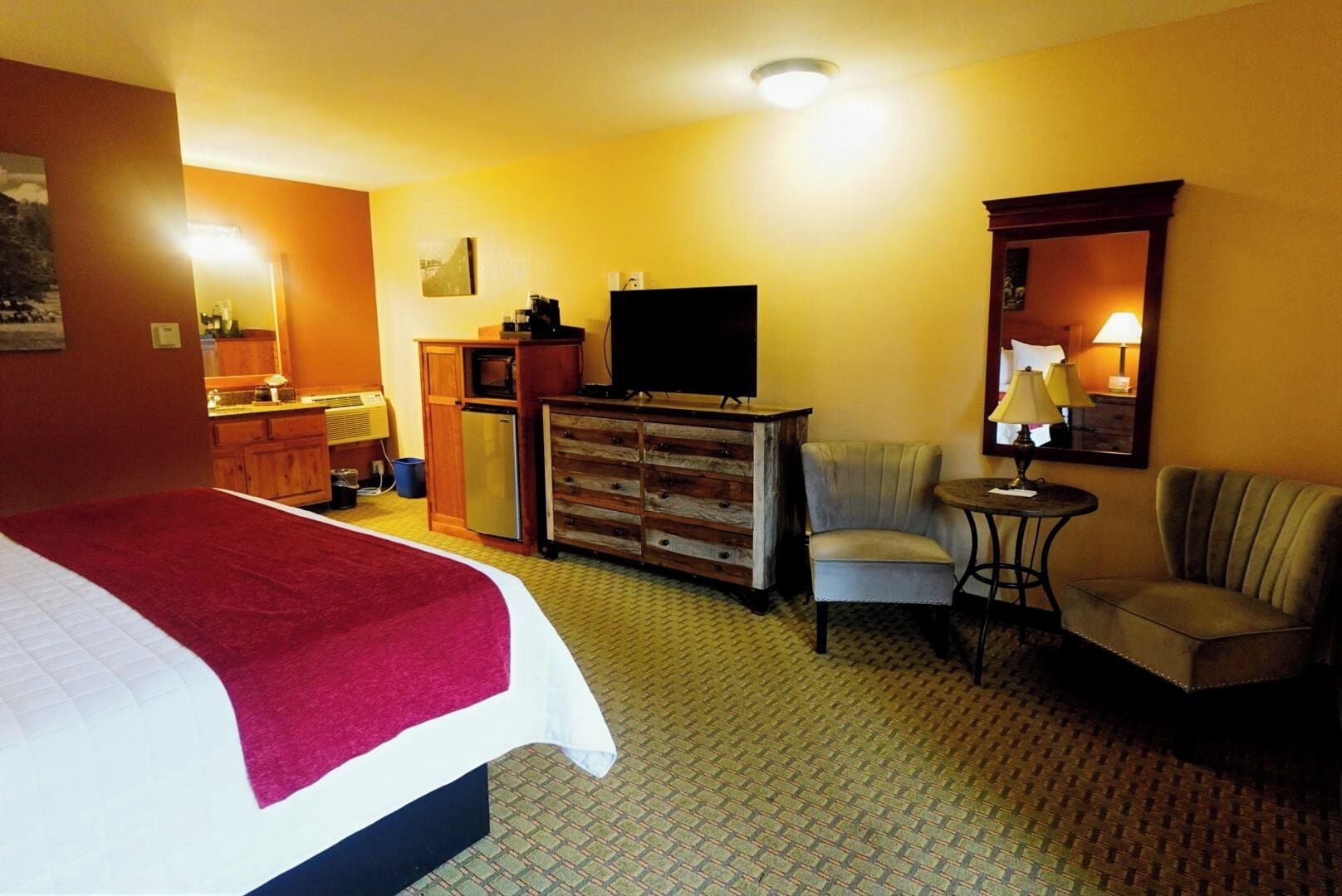 A hotel room with a bed, a television, a chair, a desk, and a dresser.