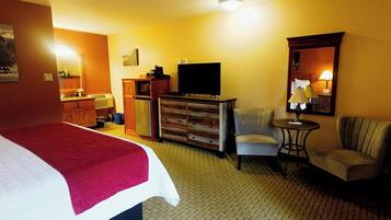 A hotel room with a bed, a television, a chair, a desk, and a dresser.