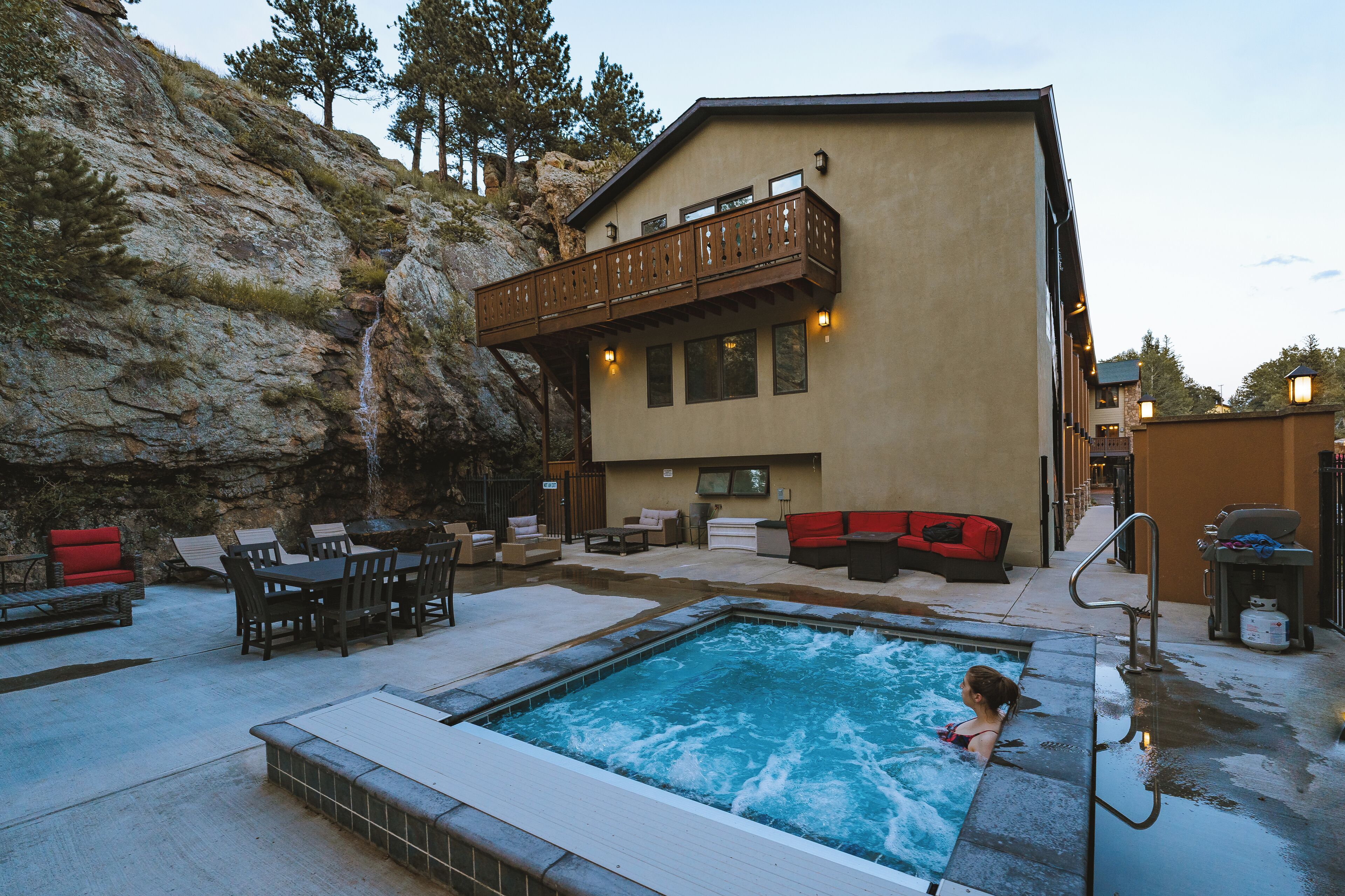 A pool area with a hot tub, outdoor seating, and a building with a balcony.